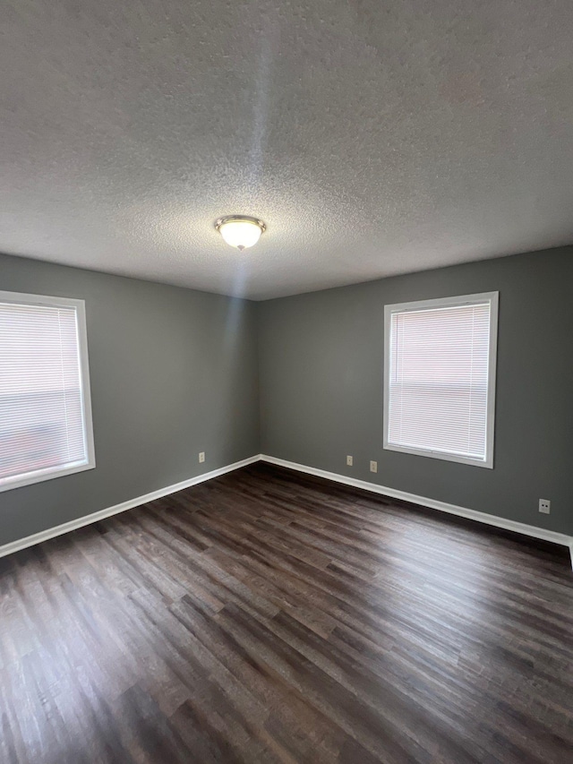 empty room with dark hardwood / wood-style floors and a textured ceiling