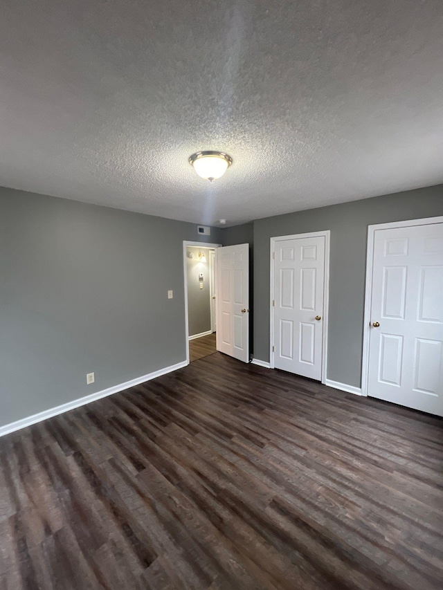 unfurnished bedroom with a textured ceiling and dark hardwood / wood-style flooring