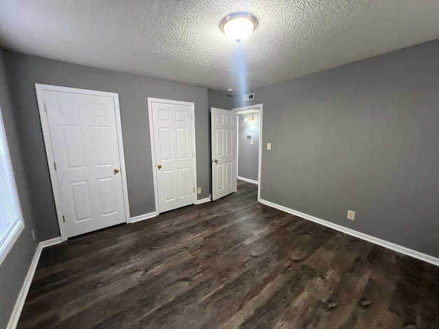 unfurnished bedroom with a textured ceiling and dark wood-type flooring