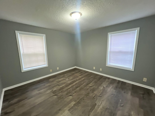 spare room featuring dark wood-type flooring and a textured ceiling