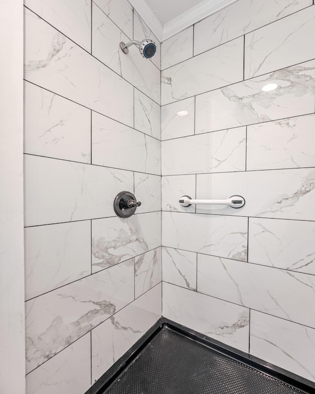 bathroom with crown molding and a tile shower