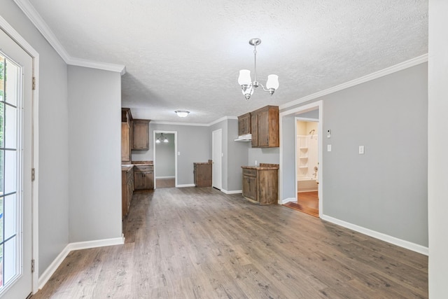 interior space with hardwood / wood-style floors, a notable chandelier, pendant lighting, a textured ceiling, and crown molding