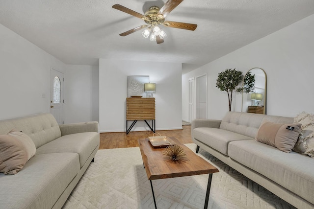 living room with light hardwood / wood-style floors, a textured ceiling, and ceiling fan