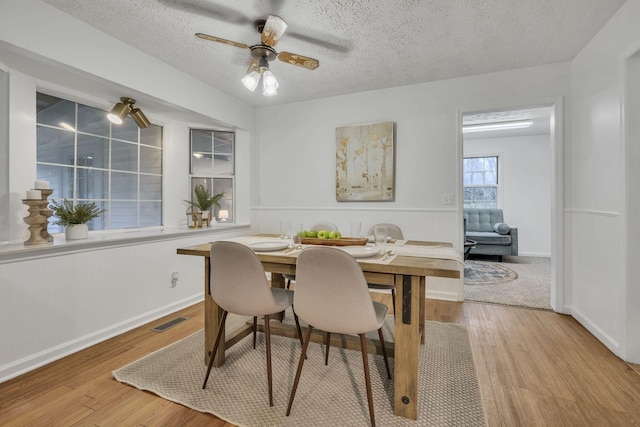 dining area with ceiling fan, a textured ceiling, and light hardwood / wood-style floors