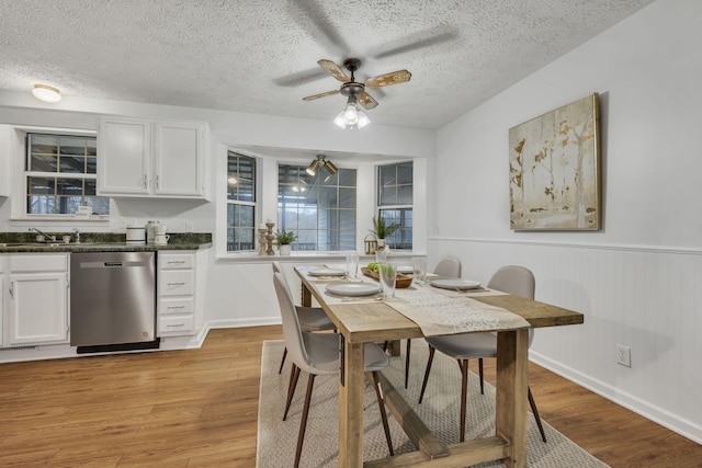 dining area featuring a textured ceiling, ceiling fan, light hardwood / wood-style flooring, and sink