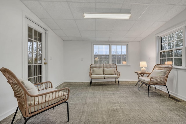 living area featuring a paneled ceiling and light carpet