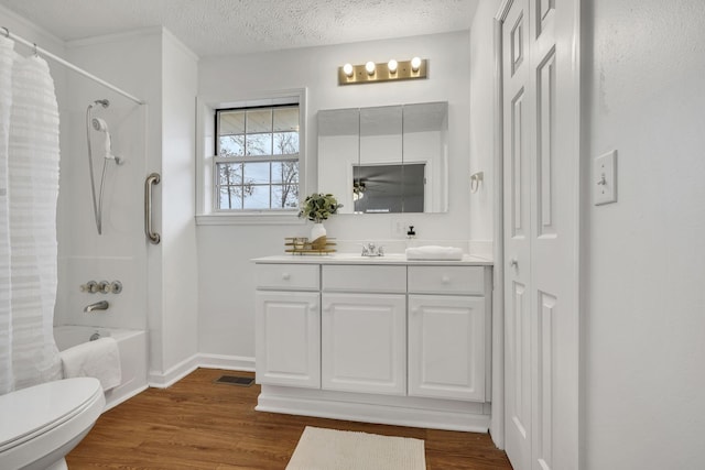 full bathroom featuring toilet, vanity, shower / bath combo, hardwood / wood-style floors, and a textured ceiling