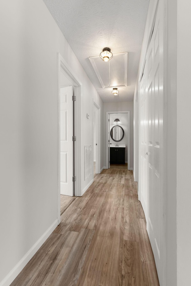 hall featuring light hardwood / wood-style floors and a textured ceiling