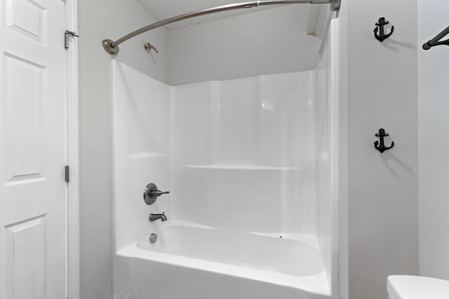 bathroom featuring toilet, shower / bathing tub combination, and a textured ceiling