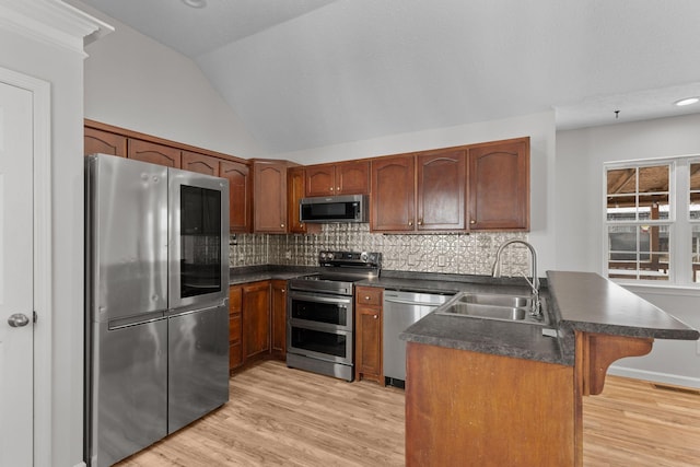 kitchen with lofted ceiling, sink, stainless steel appliances, tasteful backsplash, and light wood-type flooring