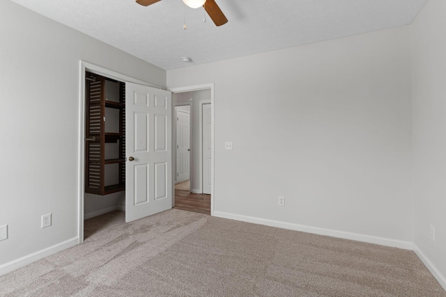 unfurnished bedroom with ceiling fan, a closet, light carpet, and a textured ceiling