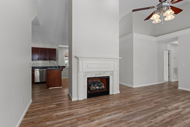 unfurnished living room with high vaulted ceiling, sink, dark hardwood / wood-style flooring, ceiling fan, and a high end fireplace