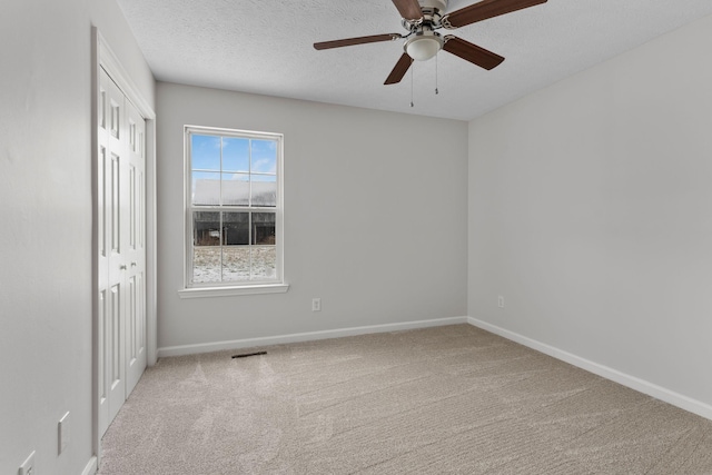 unfurnished room with light carpet, ceiling fan, and a textured ceiling