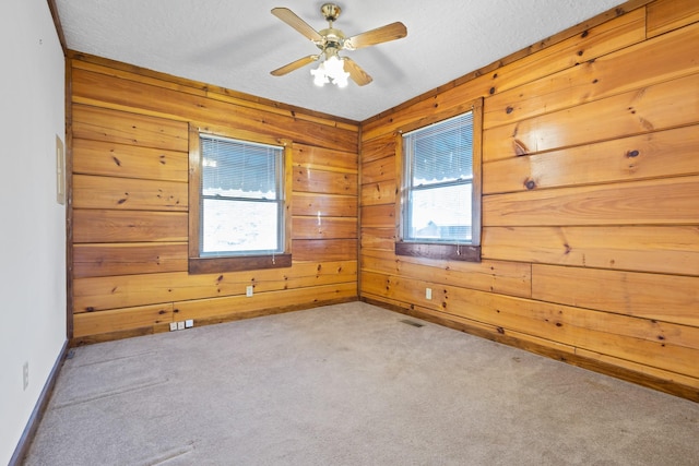 carpeted empty room with ceiling fan, a textured ceiling, and wood walls