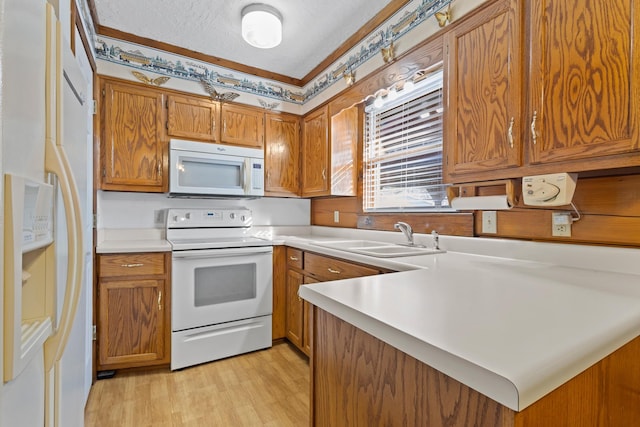 kitchen featuring sink, a textured ceiling, light hardwood / wood-style flooring, kitchen peninsula, and white appliances