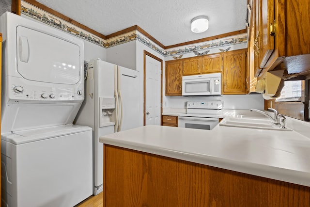 kitchen with sink, stacked washer and clothes dryer, white appliances, kitchen peninsula, and a textured ceiling