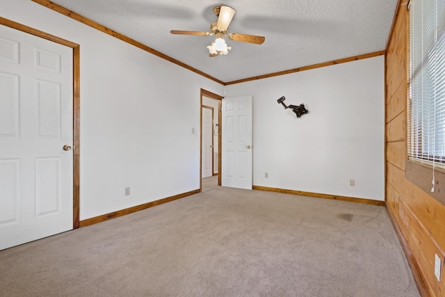 spare room with ceiling fan, ornamental molding, light carpet, and a textured ceiling