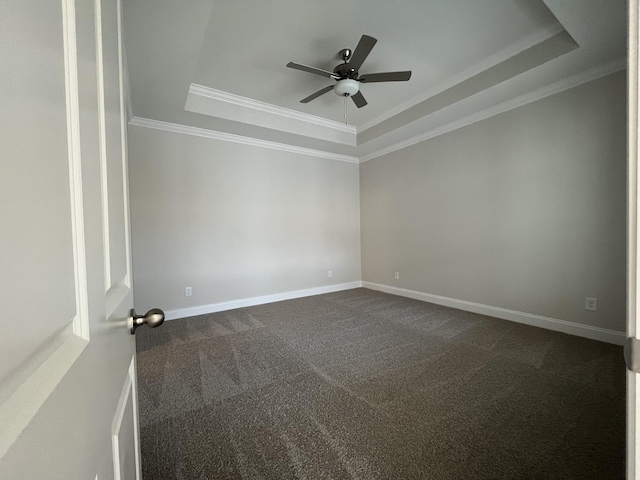 carpeted empty room with ceiling fan, ornamental molding, and a raised ceiling