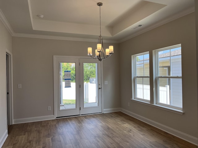 interior space with dark wood-type flooring, an inviting chandelier, ornamental molding, and a raised ceiling