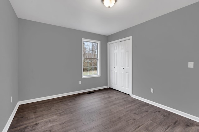 unfurnished bedroom featuring dark wood-type flooring and a closet