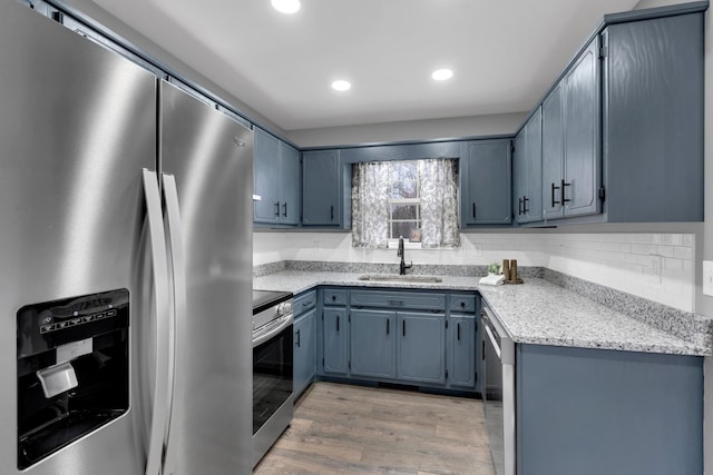 kitchen featuring tasteful backsplash, sink, hardwood / wood-style flooring, appliances with stainless steel finishes, and light stone counters