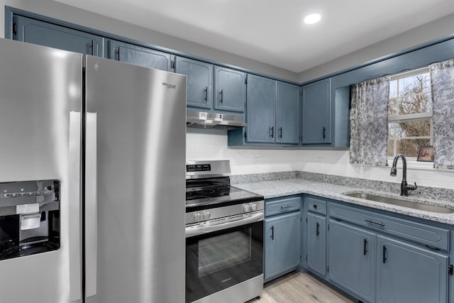 kitchen featuring appliances with stainless steel finishes, sink, light stone counters, light hardwood / wood-style flooring, and blue cabinets