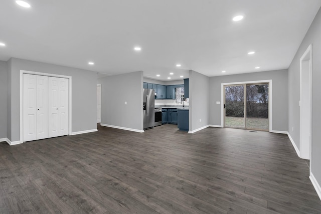 unfurnished living room featuring sink and dark hardwood / wood-style flooring