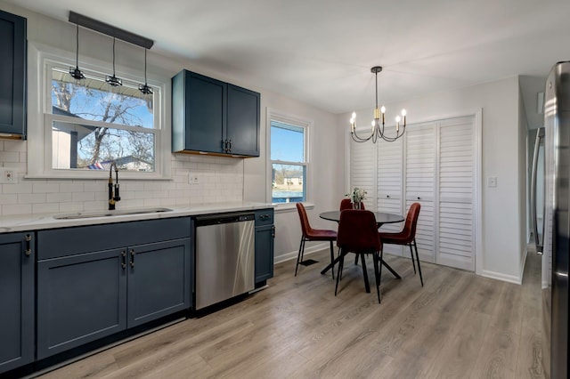 kitchen with light hardwood / wood-style floors, stainless steel appliances, decorative backsplash, hanging light fixtures, and sink