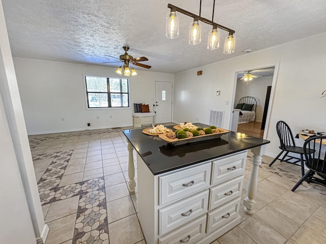 kitchen featuring hanging light fixtures, a center island, white cabinets, and ceiling fan