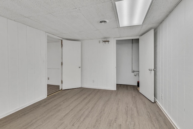 spare room with a paneled ceiling and light hardwood / wood-style floors