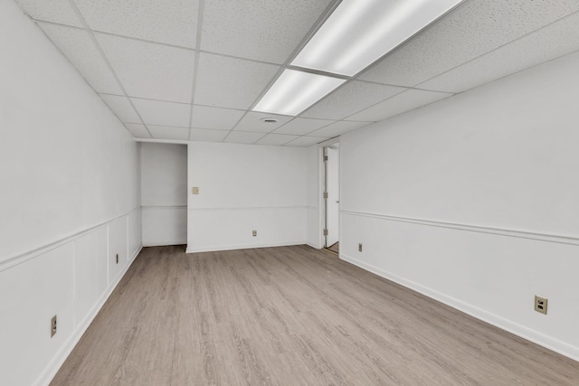 basement with light wood-type flooring and a paneled ceiling