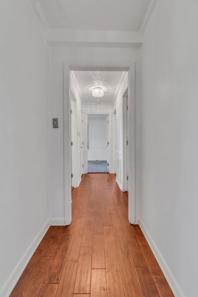 corridor featuring a textured ceiling and ornamental molding