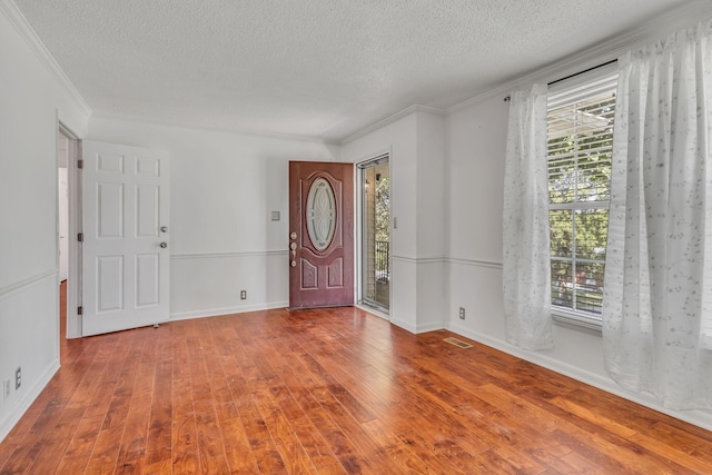 foyer entrance featuring a textured ceiling, crown molding, and hardwood / wood-style floors