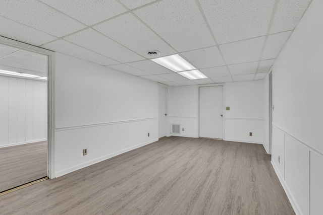 spare room with a paneled ceiling and light hardwood / wood-style flooring