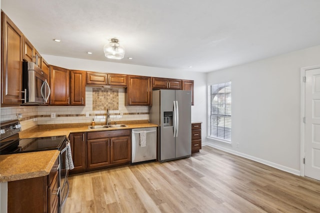 kitchen featuring sink, stainless steel appliances, light hardwood / wood-style flooring, and backsplash