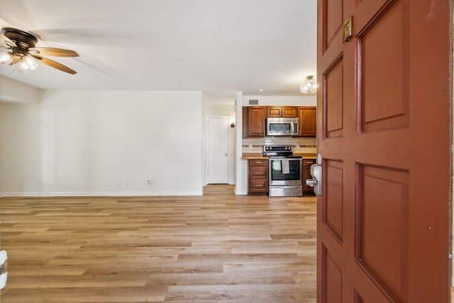 kitchen with decorative backsplash, appliances with stainless steel finishes, ceiling fan, and light wood-type flooring