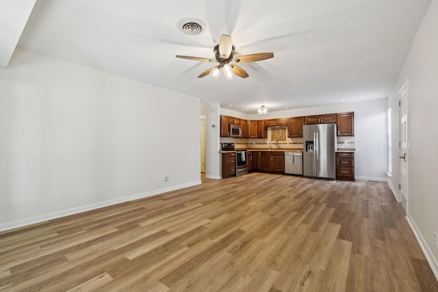 unfurnished living room with light hardwood / wood-style floors, sink, and ceiling fan