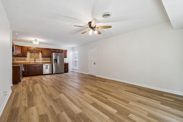 unfurnished living room with light wood-type flooring, ceiling fan, and sink