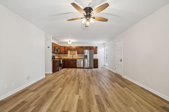 unfurnished living room featuring sink, light wood-type flooring, and ceiling fan