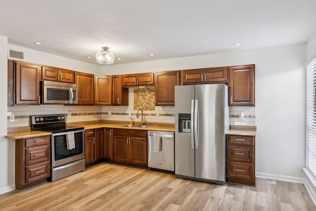 kitchen featuring sink, light hardwood / wood-style floors, a healthy amount of sunlight, and stainless steel appliances