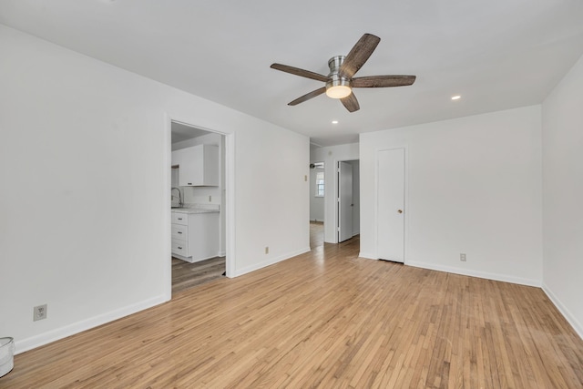 unfurnished bedroom featuring ensuite bathroom, sink, ceiling fan, and light wood-type flooring