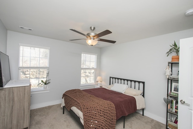 bedroom featuring ceiling fan, light colored carpet, and multiple windows