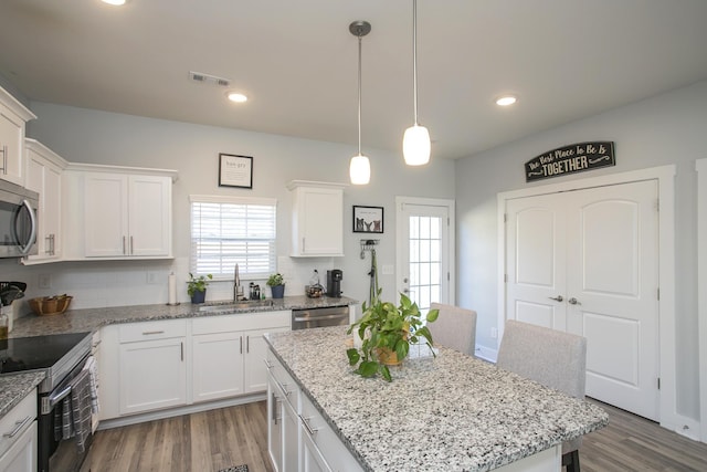 kitchen with backsplash, a center island, sink, white cabinetry, and appliances with stainless steel finishes