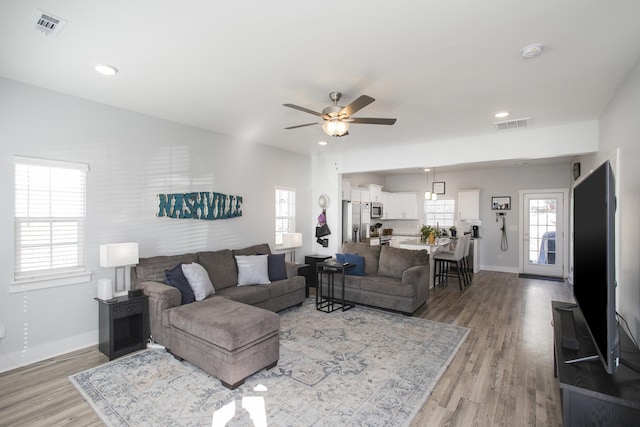 living room with ceiling fan and light wood-type flooring