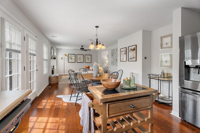 dining room with dark wood-type flooring and ceiling fan with notable chandelier