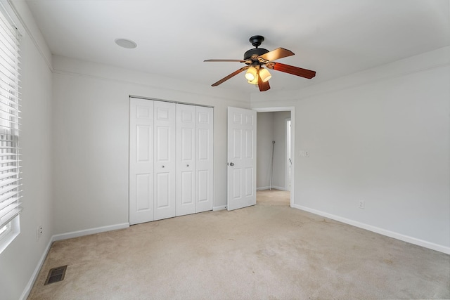 unfurnished bedroom featuring ceiling fan, light colored carpet, and a closet