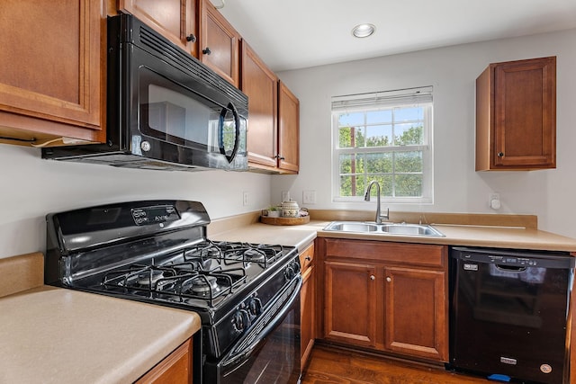 kitchen with sink, dark hardwood / wood-style floors, and black appliances