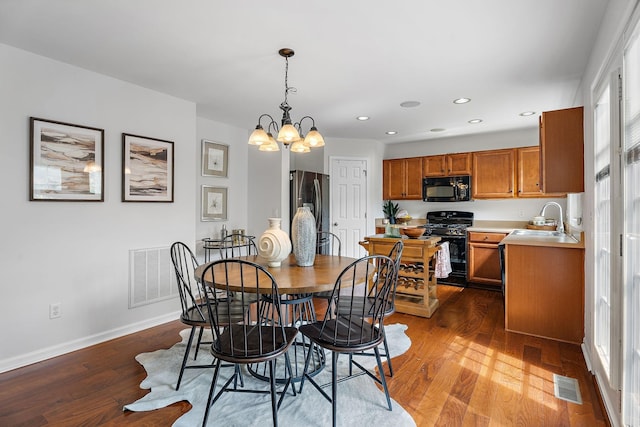 dining area with a notable chandelier, dark wood-type flooring, and sink