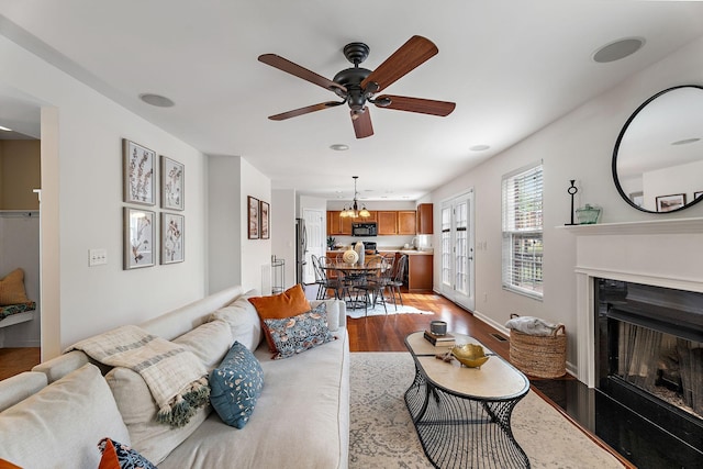 living room with light wood-type flooring and ceiling fan with notable chandelier