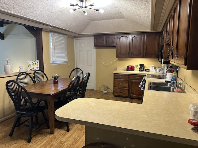 dining space featuring an inviting chandelier, a tray ceiling, a textured ceiling, light hardwood / wood-style flooring, and sink